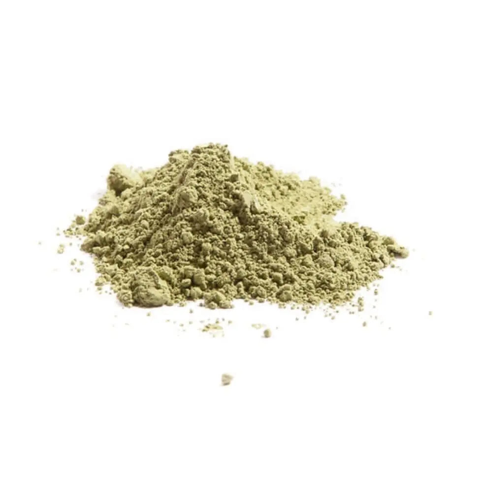 Un petit tas de poudre fine d'Indigo pour cheveux Indigofera tinctoria brun verdâtre de La Sultana Savonnerie | Savons et soins naturels faits main | Le Québec est dispersé sur une surface unie et blanche. La poudre semble lâchement tassée avec quelques amas et quelques taches réparties autour du tas principal.