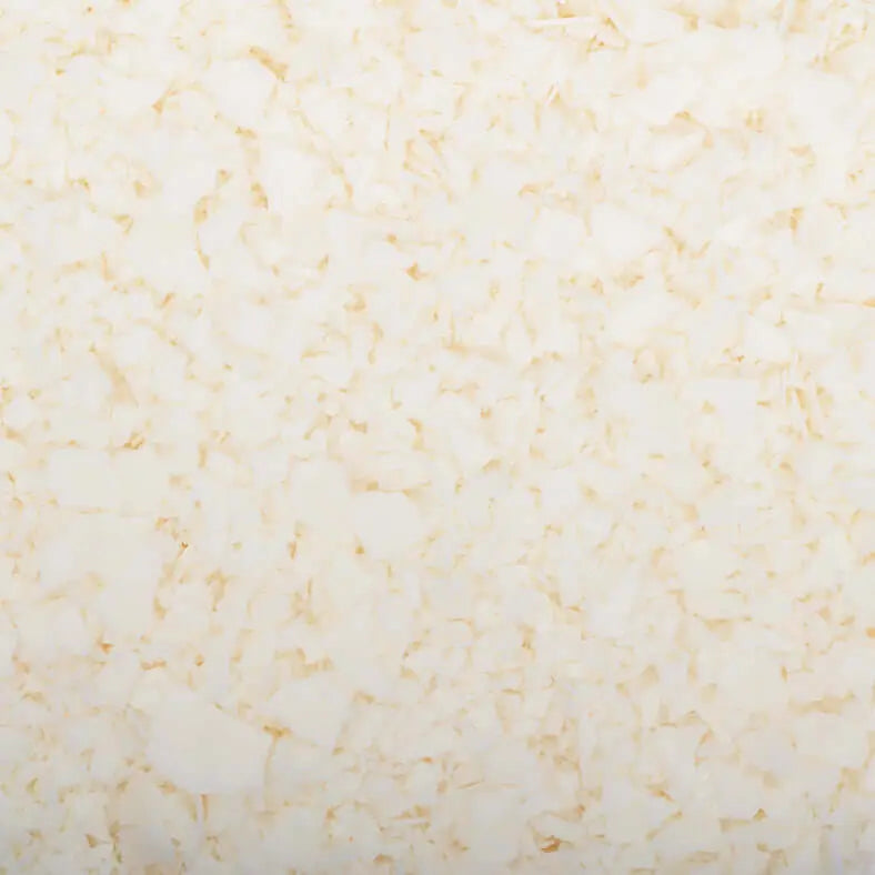 Gros plan d'une texture composée de nombreux petits flocons blancs fabriqués à partir de la cire de soja 444 Golden Brand de La Sultana Savonnerie. Les flocons varient en taille et en forme, créant un motif irrégulier mais uniforme. L'apparence générale est plate avec une couleur blanc crème uniforme, rappelant les bougies faites maison de haute qualité fabriquées au Québec.